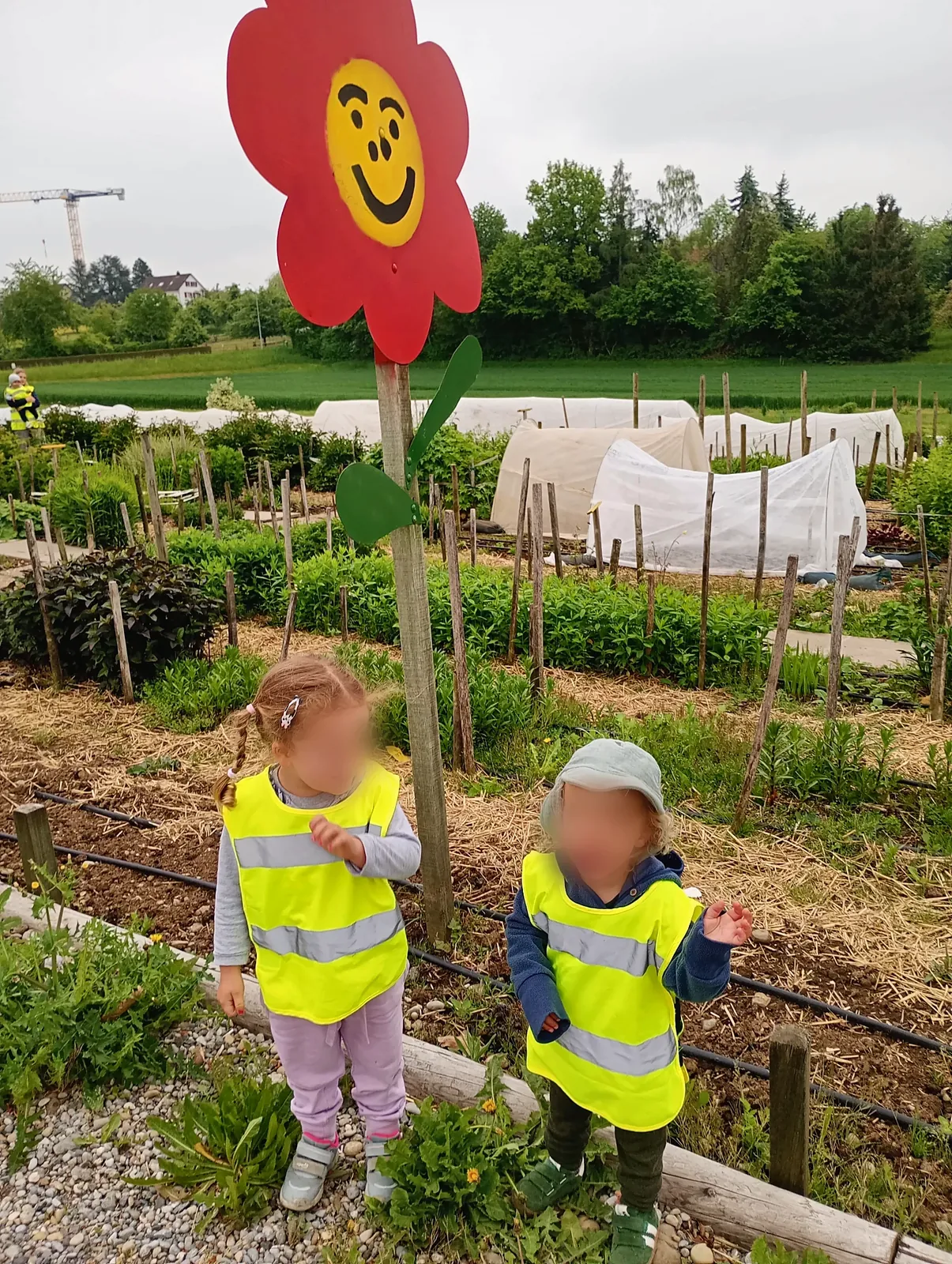 Zwei Kinder im Gemüsegarten bei der Blumen-Figur